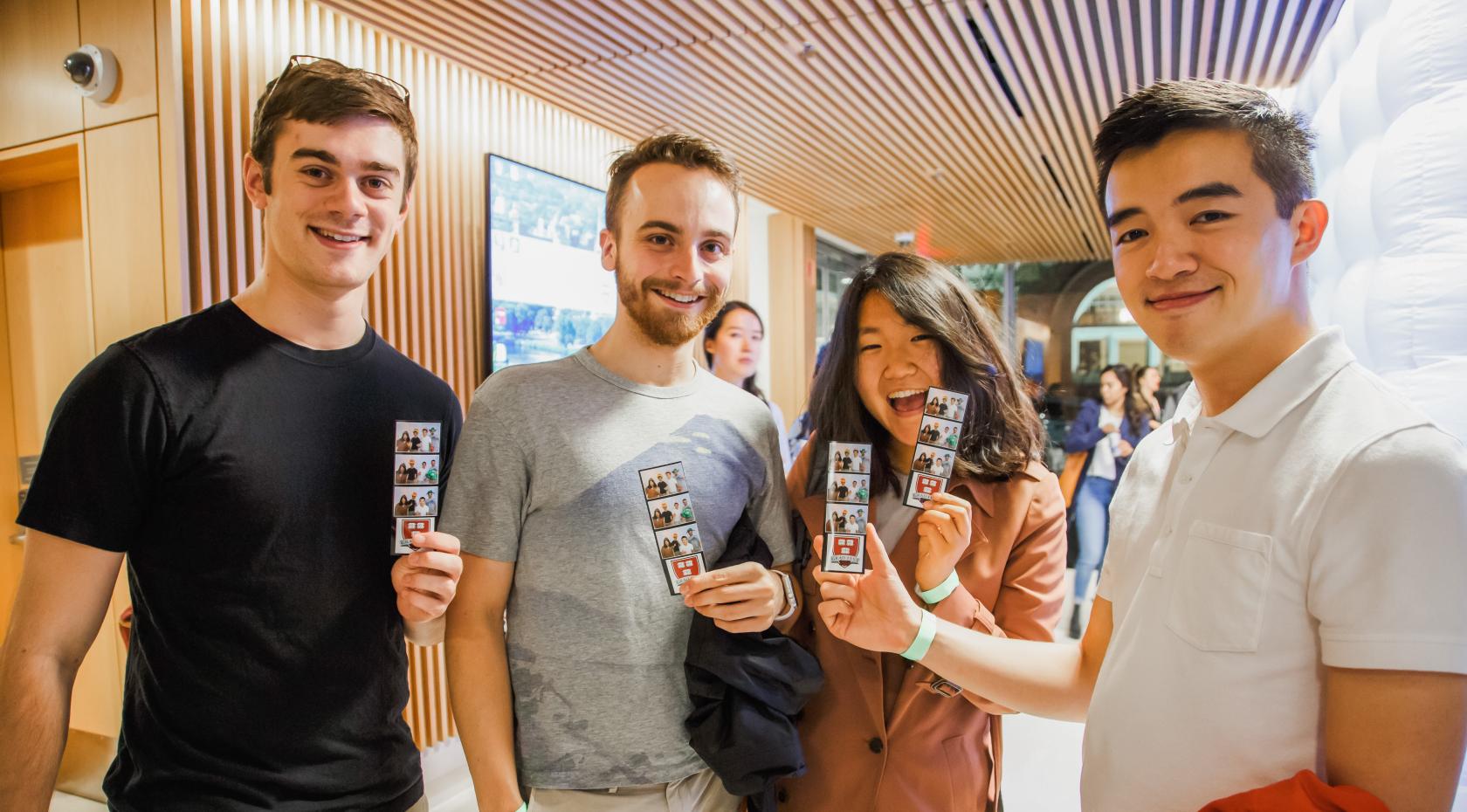 Some residents enthusiastically holding up some photo strips of them together from a photo booth at an HUH event