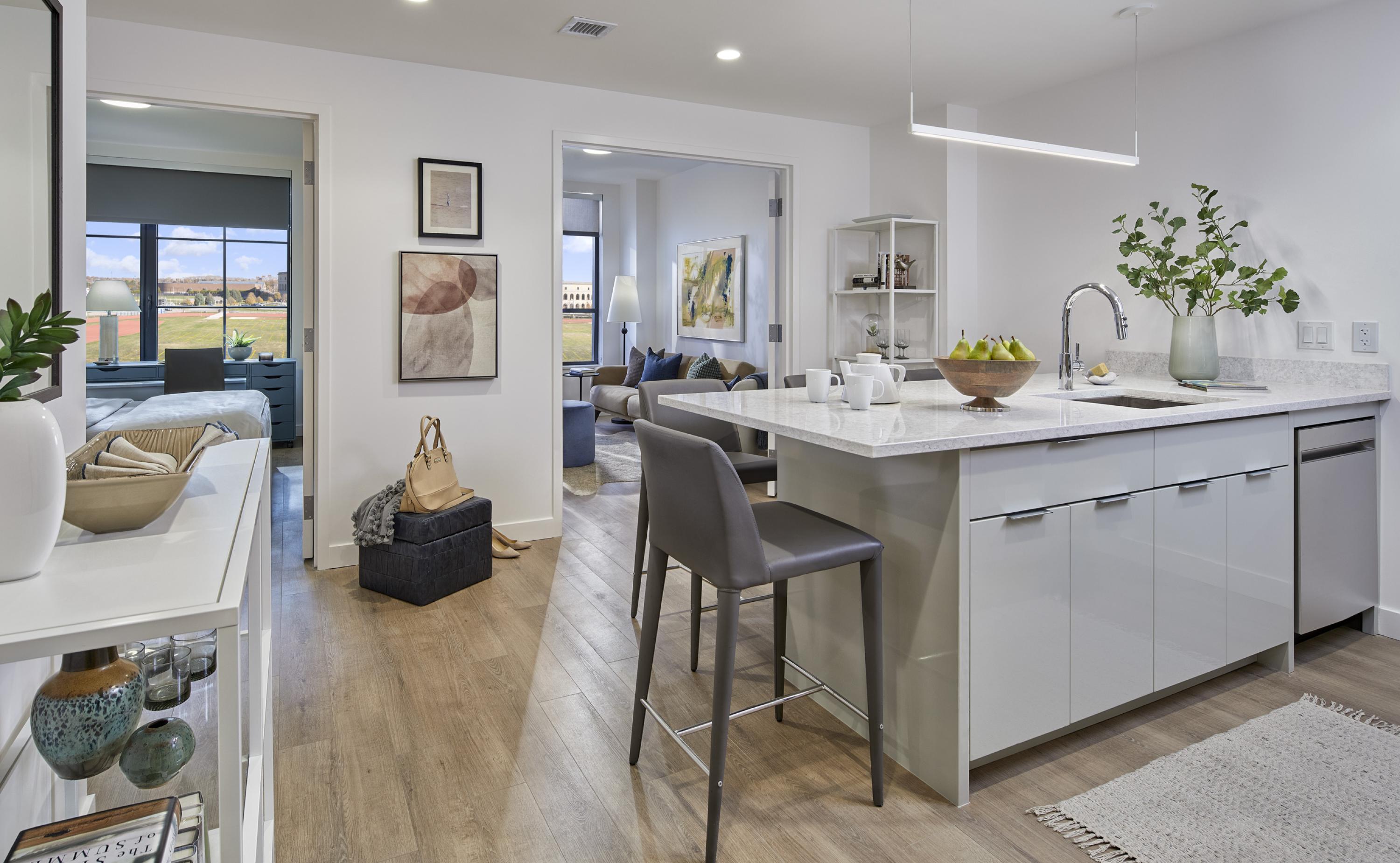 Unit entry into the shared kitchen, living, and dining area with recessed overhead lighting and hard flooring, kitchen island in full view