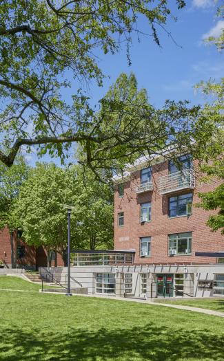 Botanic Gardens property, with green grass field in view, brick buildings in the complex, and a tree branch leaning in view