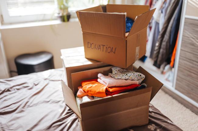 One open cardboard box stacked on top of two other boxes with the word "DONATION" written on the side in sharpie.