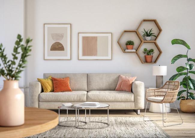 A bohemian-style decorated living room interior with beige colored furniture and hanging wall art above the couch.