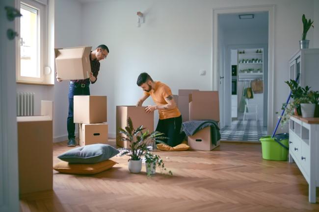 people unpacking cardboard boxes together in an empty room