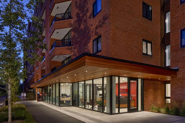 An outside view of Soldiers Field Park Property Management Office, a large brick building at night illuminated by the office lighting from the windows