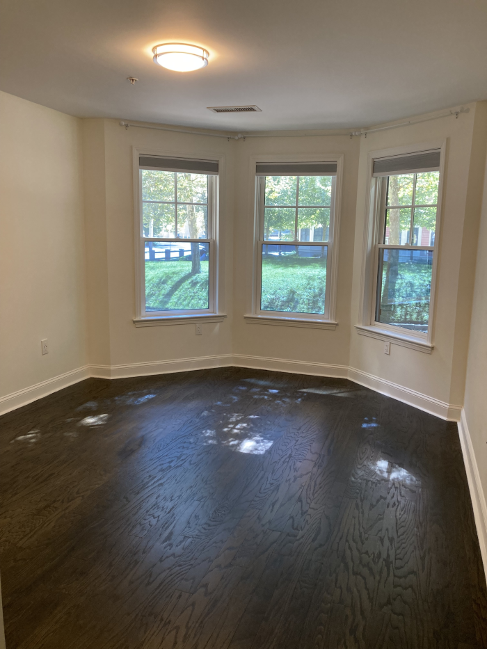 Bedroom with bay windows and dark wood flooring