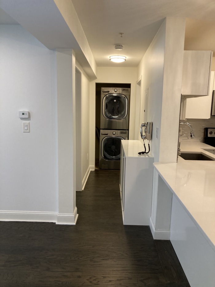 Open walkway to the laundry closet with stacked washers and dryers