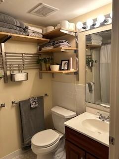 Bathroom with white toilet, sink, and dark under-sink cabinetry. Tile flooring.