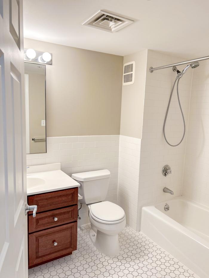 173 402 bathroom with white tile, wooden cabinetry, and a white toilet, tub, and sink.