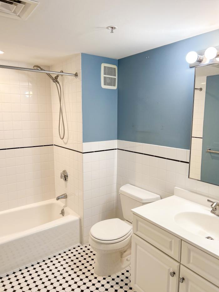 A bathroom of 173 401 - black and white floor tiles with blue walls and a white sink, toilet, and tub.
