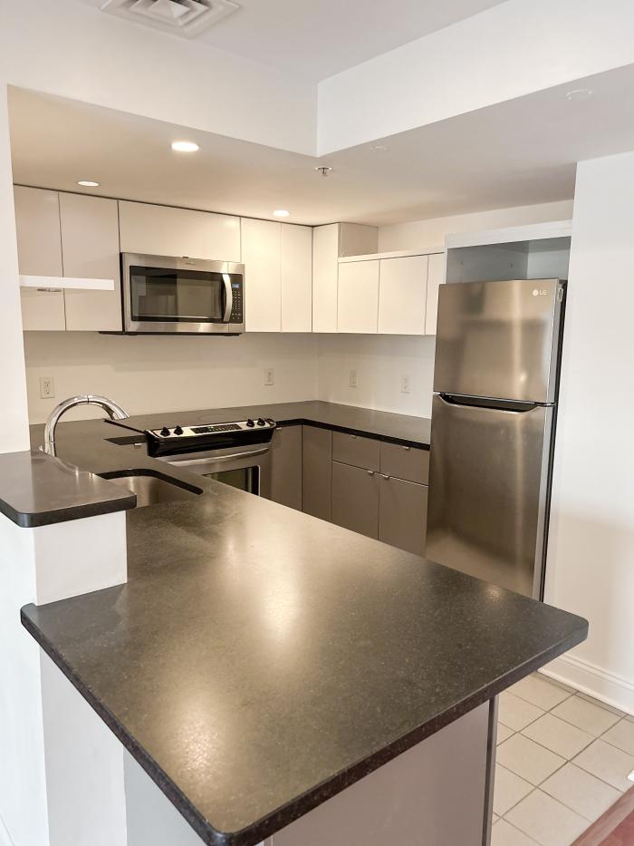The kitchen of 173 402 with white cabinetry, dark counters, and stainless steel appliances
