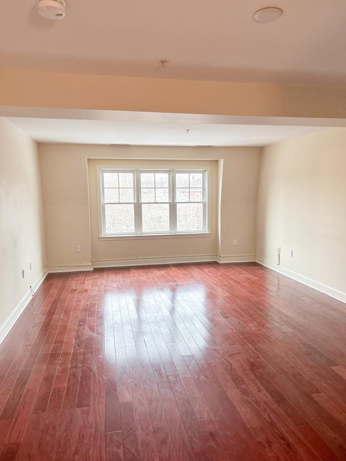 The view of the living room with bright windows, and hardwood flooring