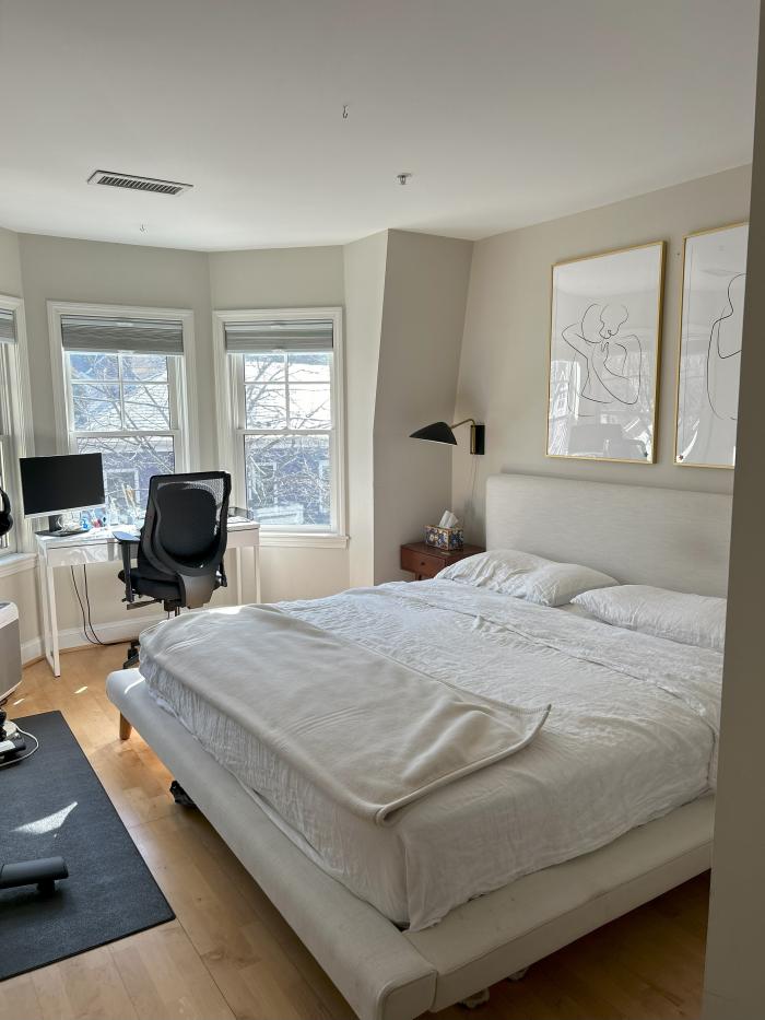 A bedroom with bay windows, off white walls and hardwood flooring. Fits a large bed.