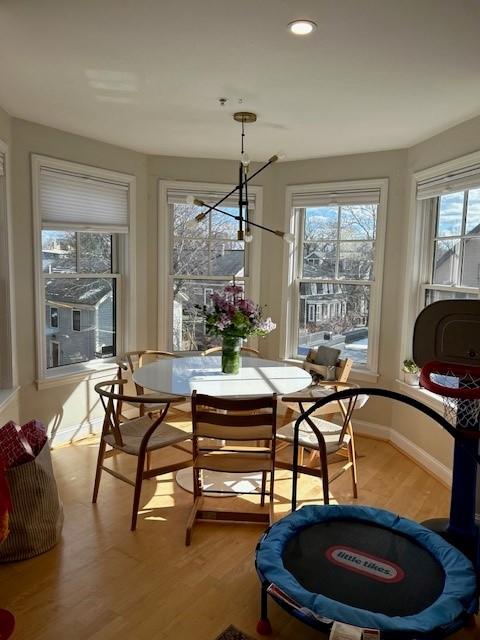 the dining area with many tall bay windows and hardwood floors. Off white walls.