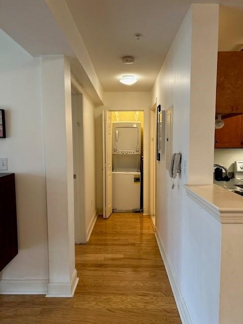 Hardwood floors leading back to the laundry closet, featuring a stacked washer and dryer