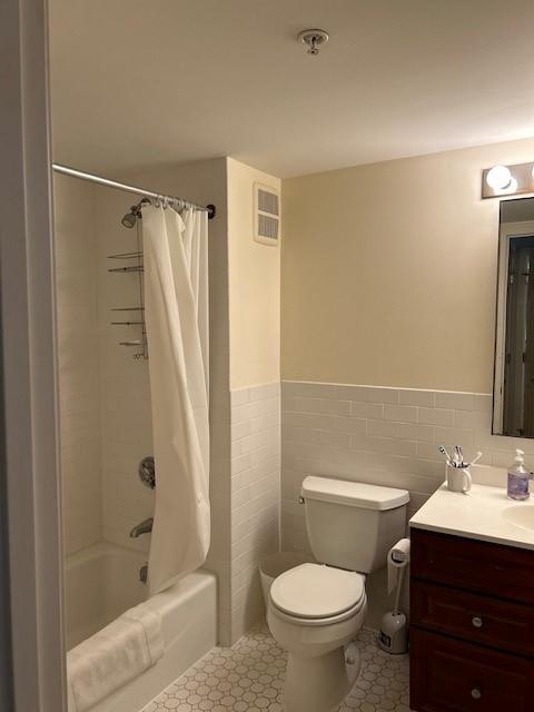 Bathroom with white tile and walls, including toilet, tub/shower, and sink with vanity
