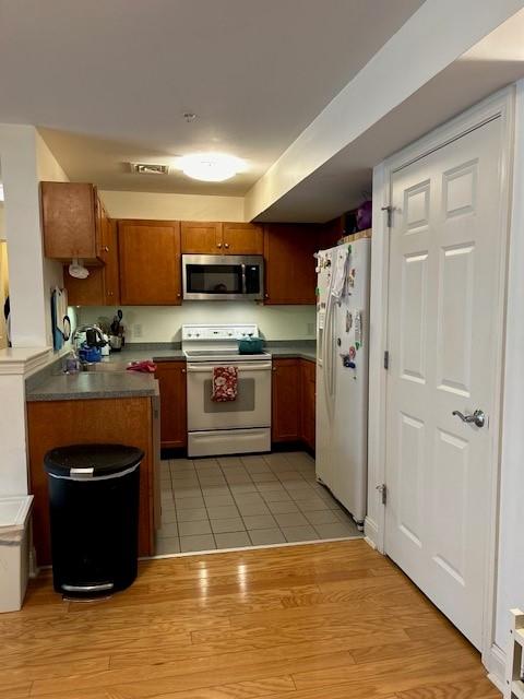 kitchen with tile flooring, wooden cabinetry, and appliances including microwave, oven/stove, and refrigerator