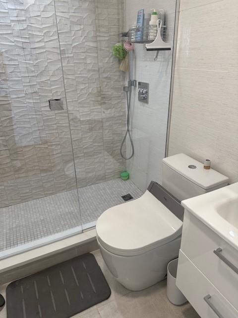 Bathroom with glass shower, white toilet, and white cabinetry
