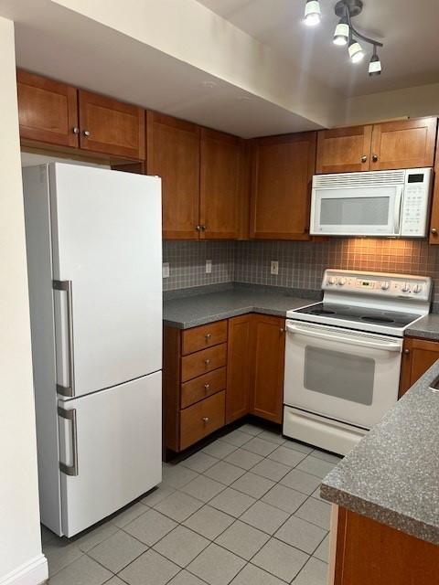 kitchen with white appliances, tiled flooring, and wooden cabinetry