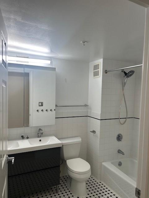 Secondary bathroom with tile flooring, white toilet, shower/tub, sink and vanity