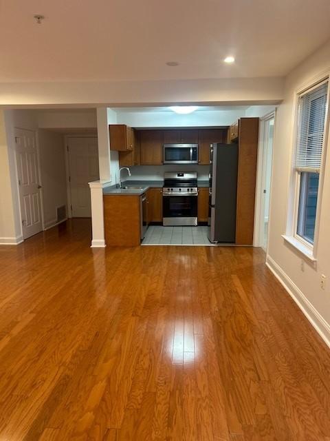 Kitchen with overhead lighting, dark wood cabinets, grey countertops, and steel appliances