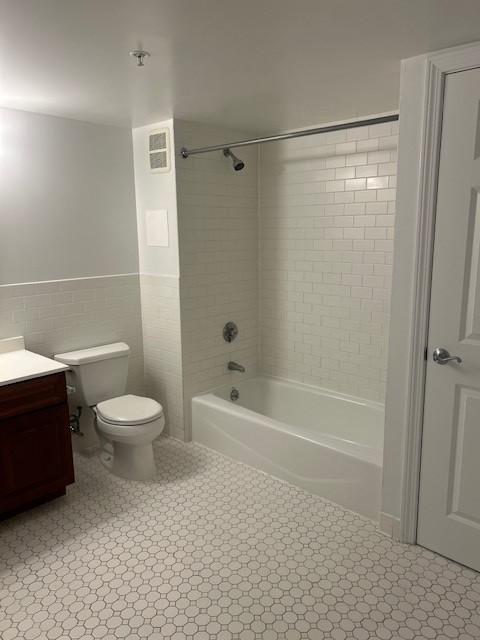 Primary bathroom with tile flooring, tub/shower combo, toilet, and sinky vanity with cabinet storage