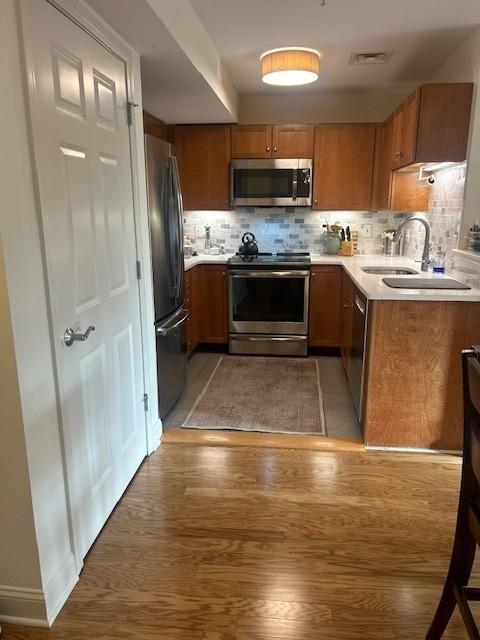 Kitchen with hard flooring, wood cabinetry, light countertops, and stainless steel appliances