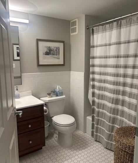Primary bathroom with tile flooring, white toilet, shower/tub, sink and vanity