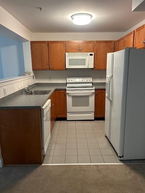 kitchen with tile flooring, white appliances, and brown cabinets. 