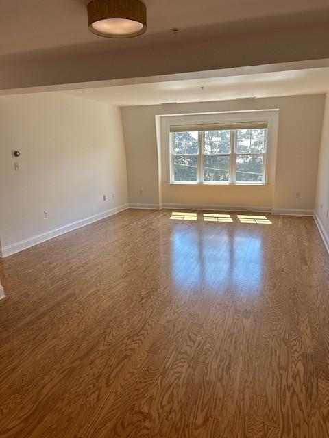 Combined living and dining area with wood flooring and large sunny windows