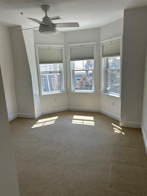 Second bedroom with carpet flooring, ceiling fan, and bay windows