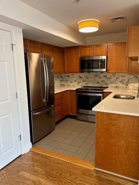Kitchen with tile flooring, stainless steel appliances, wood cabinetry and white countertops