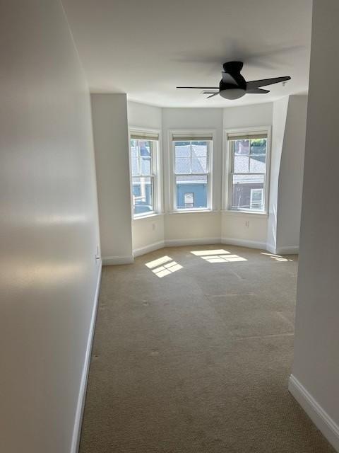 Primary bedroom with carpet floors, ceiling fan, bay windows