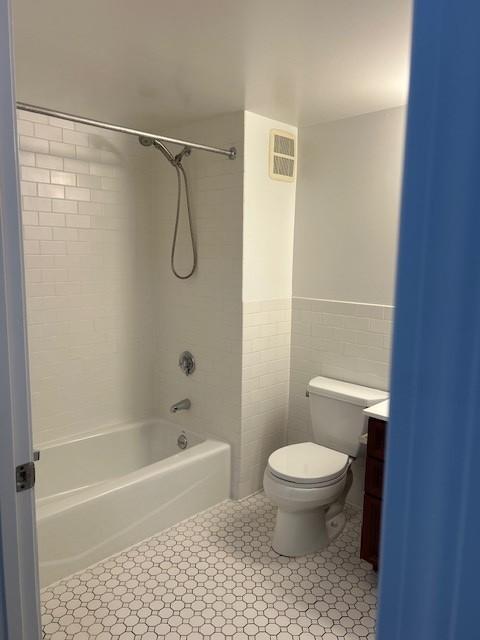 Primary bathroom with toilet, tub/shower combo, sink/vanity, and tile flooring