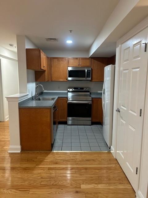 Kitchen area with wood cabinetry, stainless steel appliances, and grey countertop