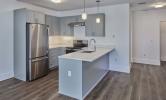 A sample kitchen in 13 Kirkland with sunny views and stainless steel appliances, recessed lighting, and pendant lighting over the kitchen island