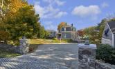 The entrance of Howells House, a blue waterfront cottage with brick pathways and white railings around the porch.