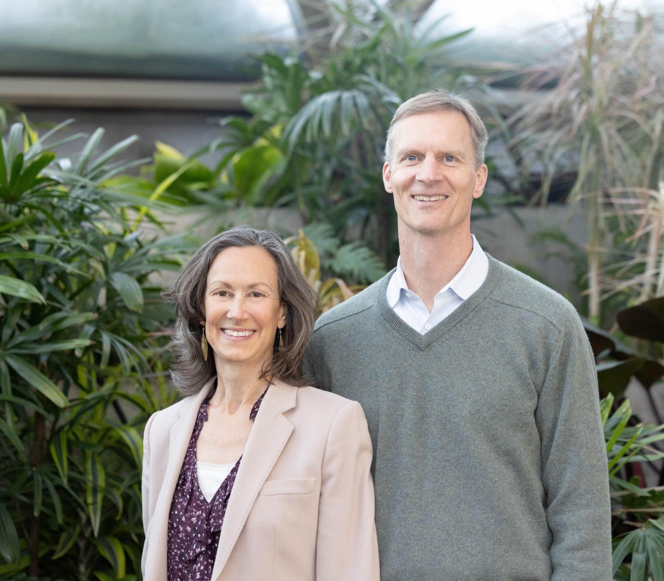HBS Professors Kathleen McGinn and Jeff Polzer smiling in front of a botanical background